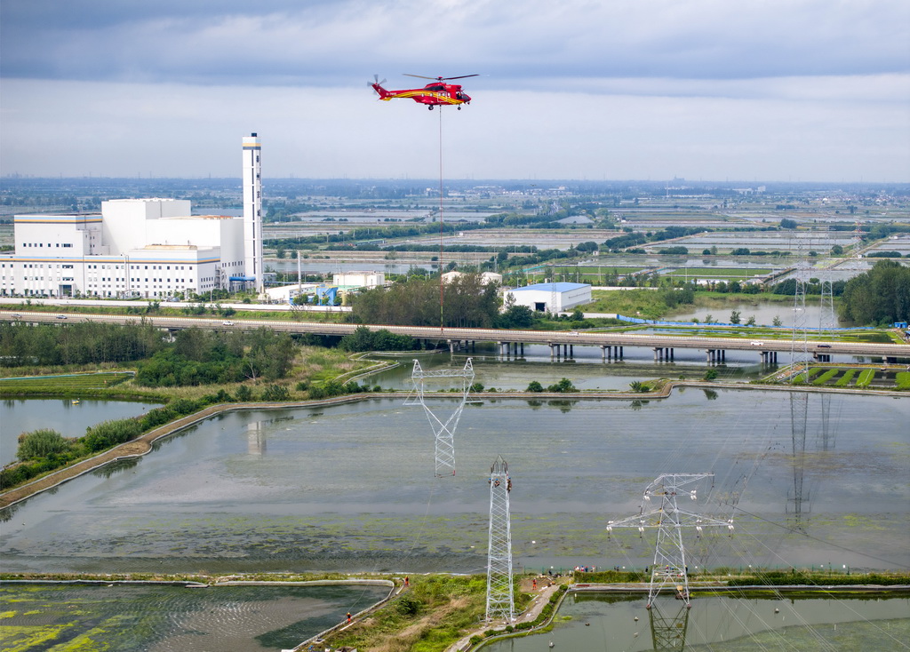 9月24日，直升機(jī)在江蘇省興化市昌榮鎮(zhèn)上空協(xié)助鐵塔架設(shè)作業(yè)（無人機(jī)照片）。新華社發(fā)（湯德宏攝）
