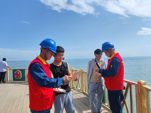 6月23日，國網(wǎng)博湖縣供電公司員工巴音達來、阿力米熱提·阿不都熱合曼為開湖季捕魚節(jié)開幕保點護航，向游客發(fā)放安全用電手冊。（王坤） (3)_副本.jpg